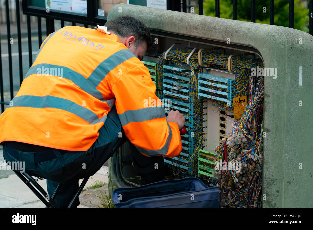 Ingegnere di BT Openreach lavora con il cablaggio alla scatola di giunzione sulla strada Foto Stock