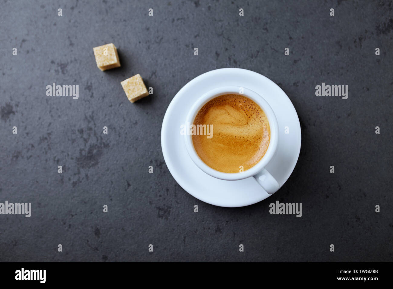 Tazza di caffè e lo zucchero di canna i cubi su pietra nera dello sfondo. Vista dall'alto. Copia dello spazio. Foto Stock