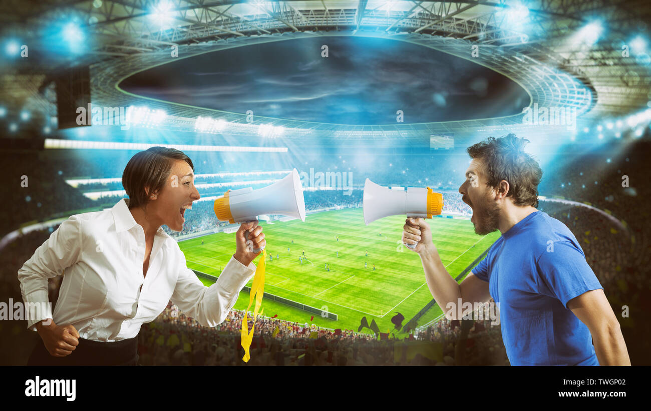 I tifosi delle squadre avversarie gridano gli uni contro gli altri con un megafono presso lo stadio durante una partita di calcio Foto Stock