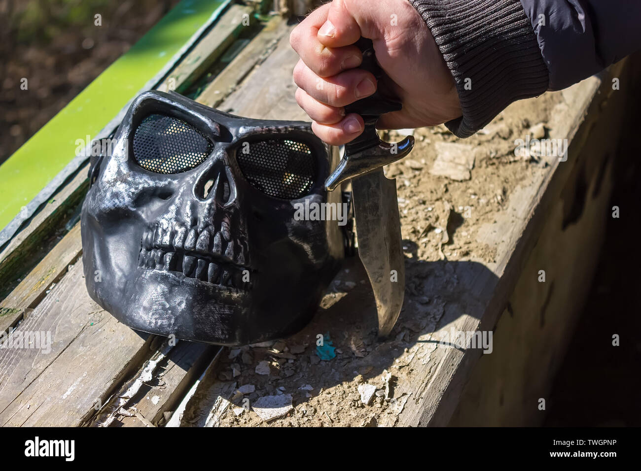 Coltello in mano e la maschera vicino alla finestra distrutta Foto Stock
