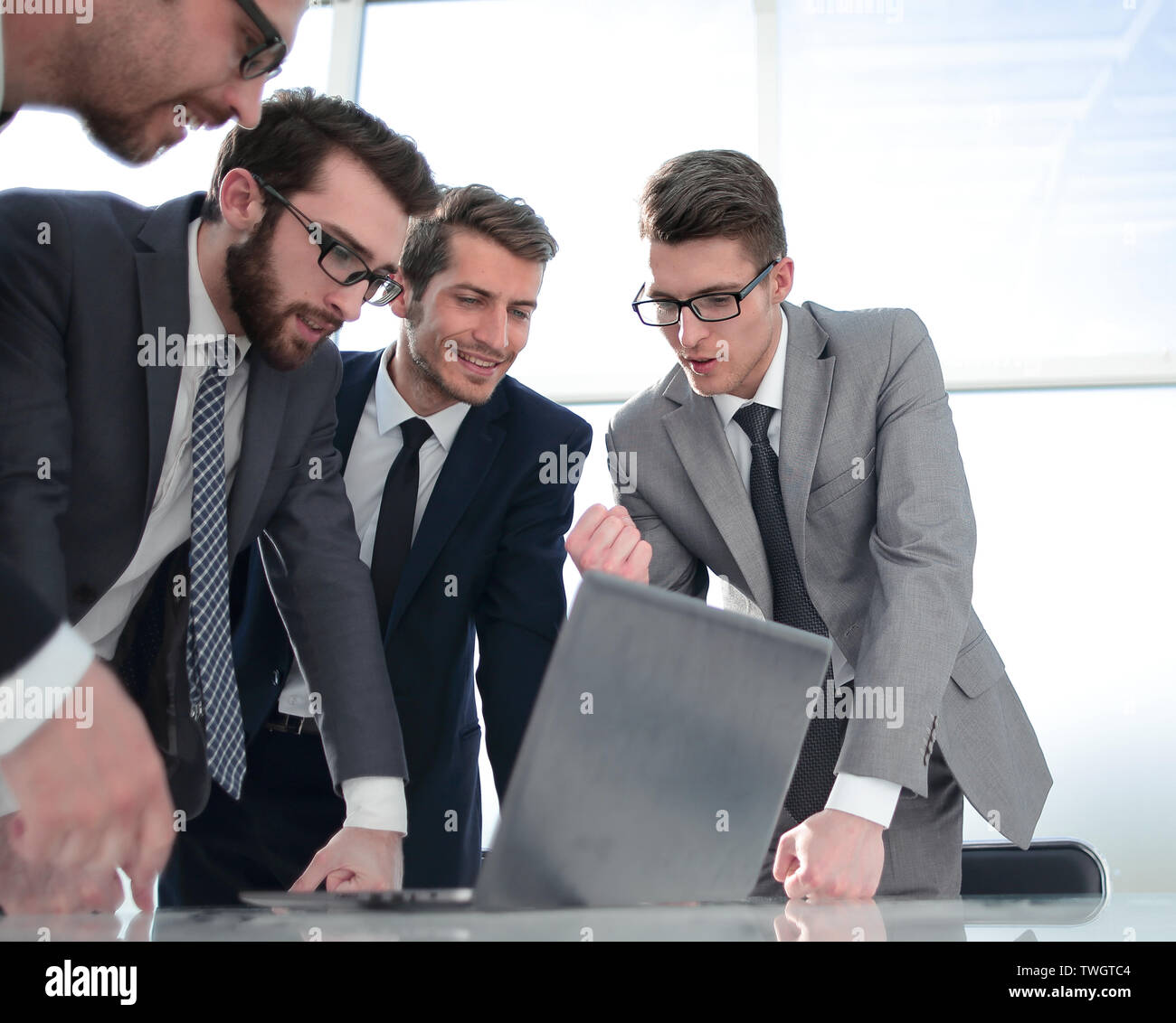 La gente di affari discutendo di qualcosa in piedi di fronte a un computer portatile aperto. Foto Stock