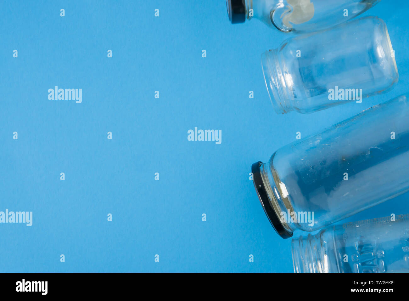 Isolato vasetti di vetro disposti di piatto su sfondo blu con vuoto camera vuota per lo spazio per il testo, copiare o copyspace sulla sinistra. Il programma per il riciclaggio o la campagna Foto Stock