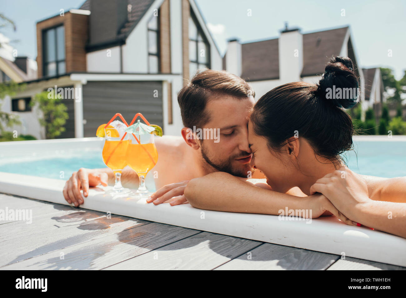 Felice coppia eterosessuale è ben riposati con cocktail mentre in piscina. Riposo estivo Foto Stock