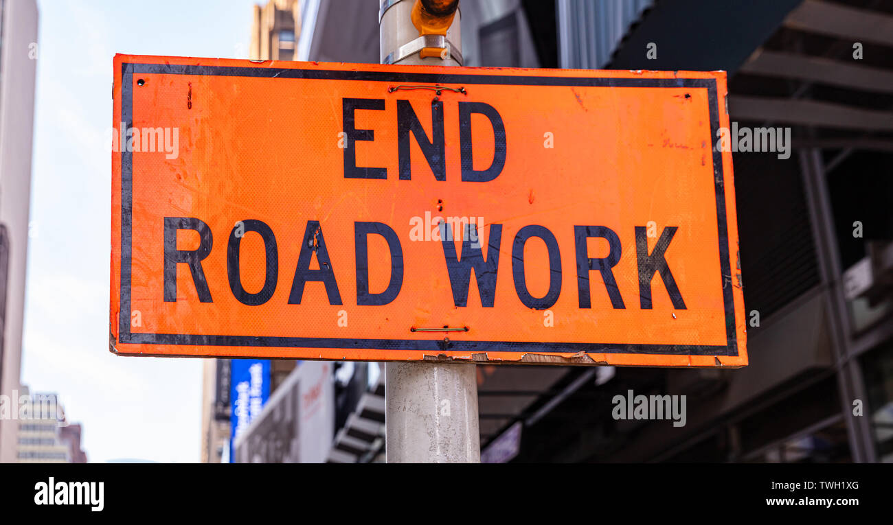 Fine lavori stradali. Strada in costruzione opere fine, segno di avvertimento, di colore arancione, blur New York city background Foto Stock