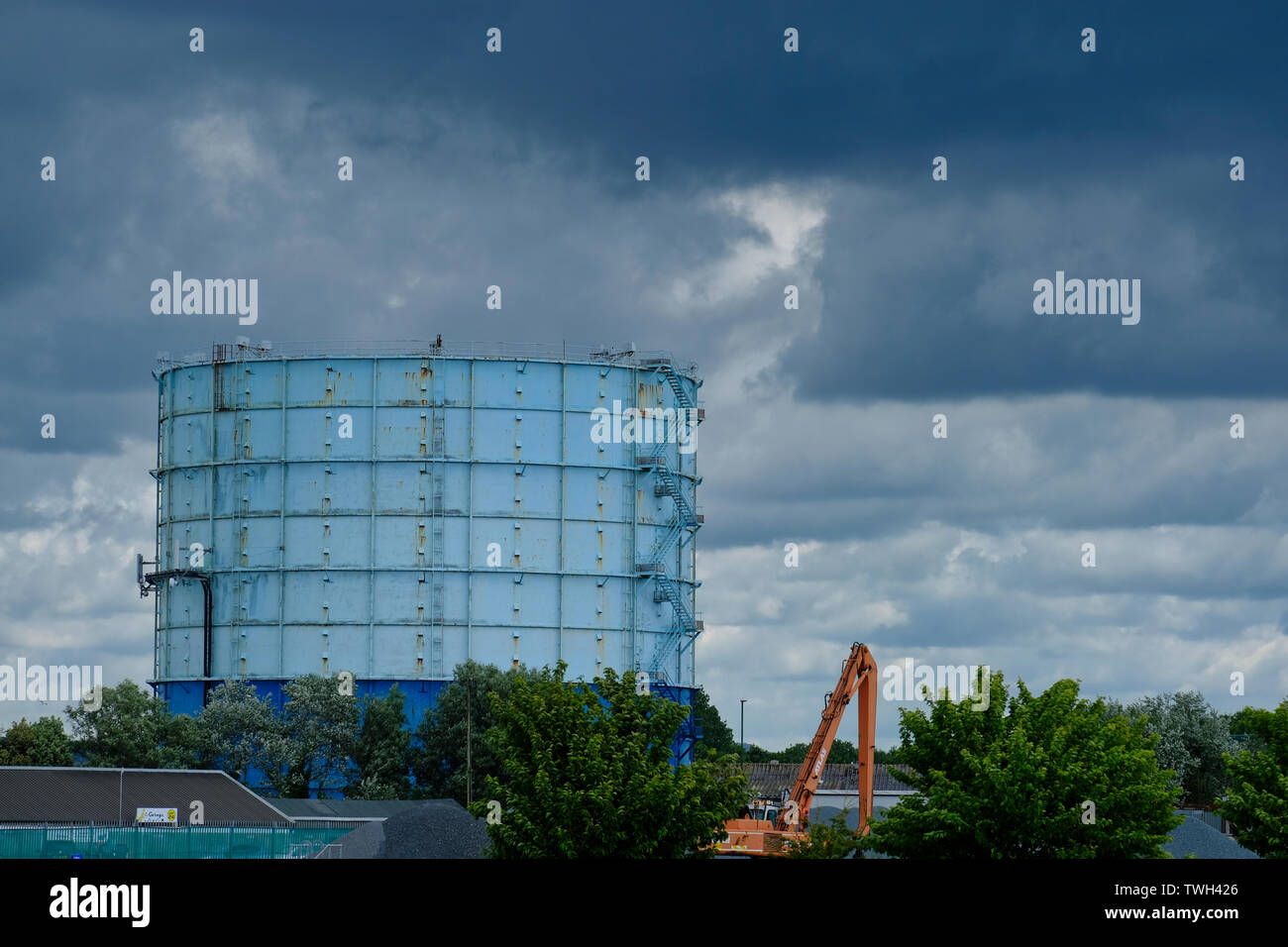 Contenitore di gas a Marina di Littlehampton, West Sussex, Regno Unito. Nuvole temporalesche formando nel cielo sopra. Questo contenitore di gas è contrassegnato per la demolizione. Foto Stock