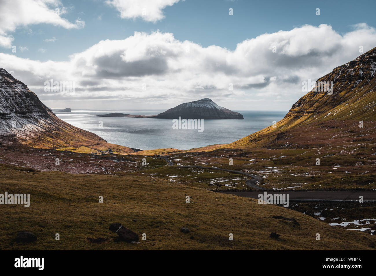 Vista sulla coperta di neve isola Koltur come visto da serpentine verso il villaggio delle Isole Faeroeer Nordradalur durante la primavera (Isole Faerøer, Danimarca) Foto Stock