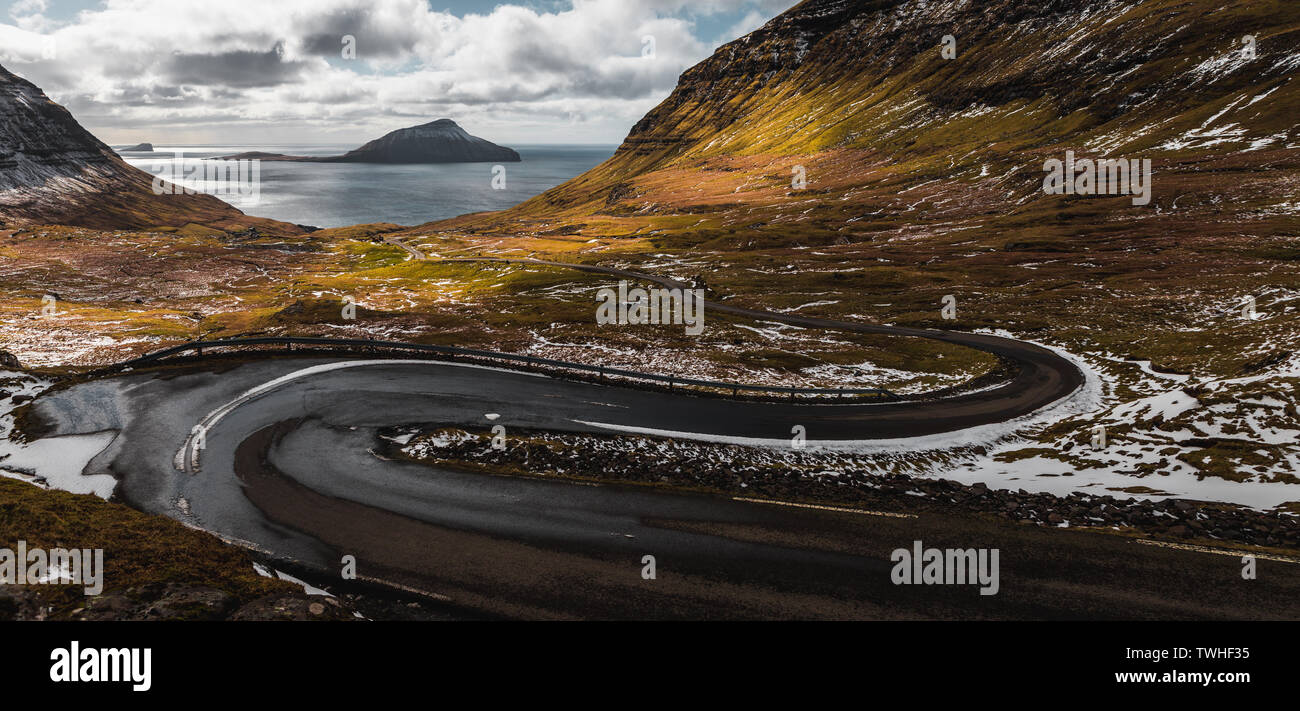 Vista sulla coperta di neve isola Koltur come visto da serpentine verso il villaggio delle Isole Faeroeer Nordradalur durante la primavera (Isole Faerøer, Danimarca) Foto Stock