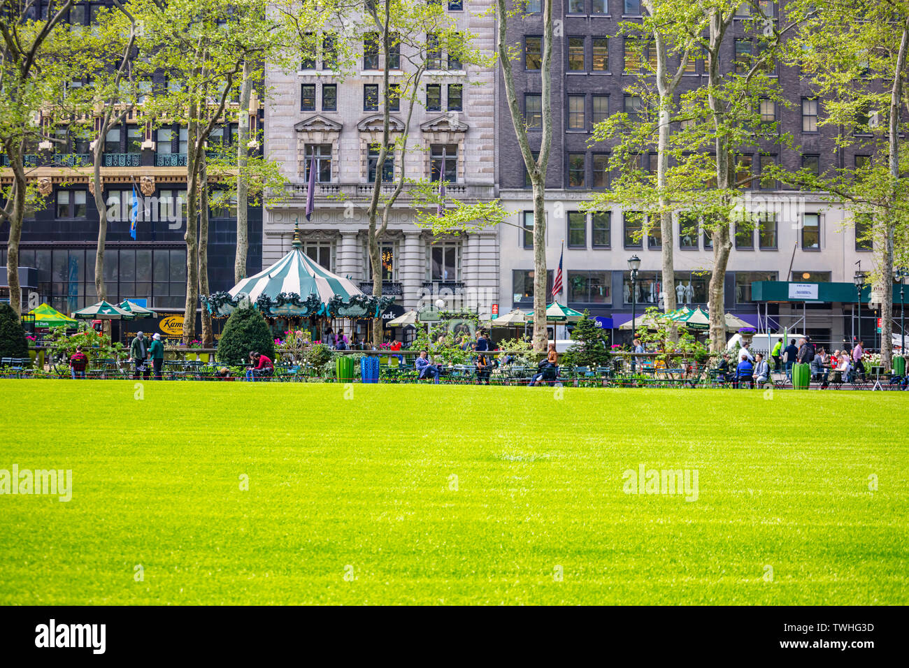 New York Manhattan Stati Uniti, Maggio 2nd, 2019. Primavera in Bryant Park. Persone rilassante, prato verde e alberi, edifici sullo sfondo Foto Stock