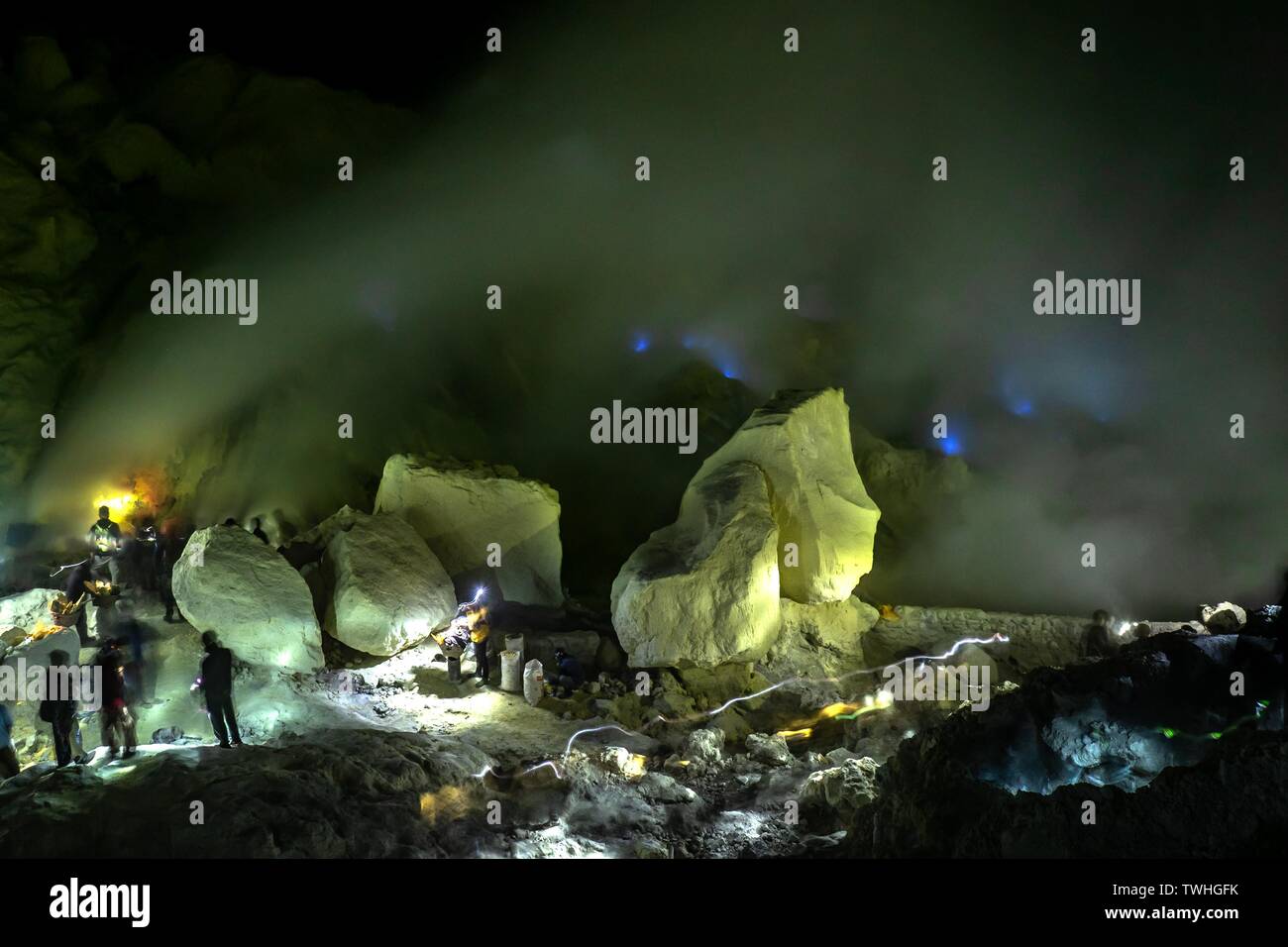 I lavoratori di tossici miniere di zolfo nella miniera di zolfo di notte, back blue fire di Vulcano Ijen, Ijen, Java, Indonesia Foto Stock