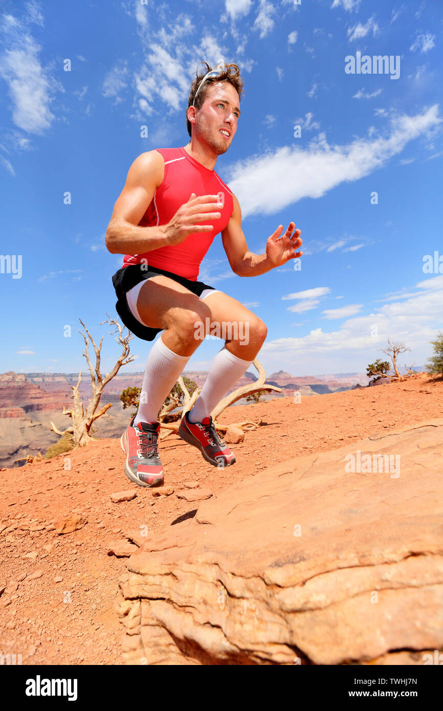 Atleta fitness bench salto squat jumping in natura paesaggio. Forza di formazione maschio adatta a lavorare fuori esercizio all'aperto in estate a fare il salto sulla roccia. Foto Stock