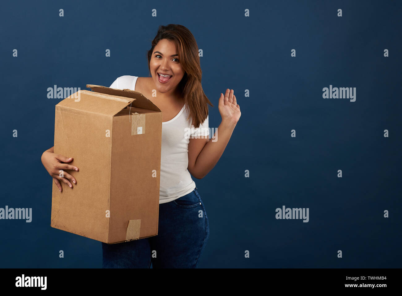 Ragazza adolescente con grande scatola di imballaggio isolato su blu di sfondo per studio Foto Stock