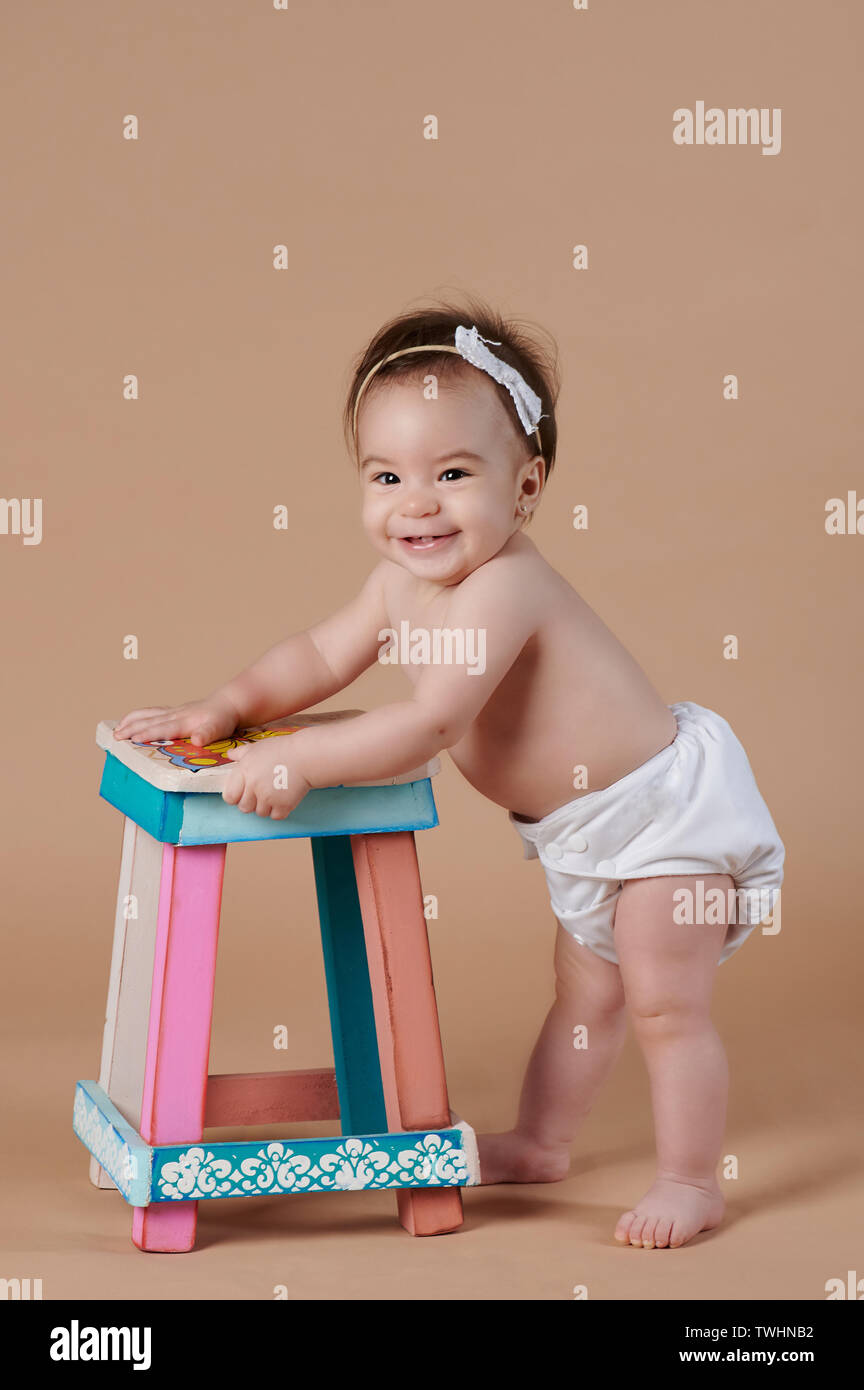 Una sorridente bambina cercando nella fotocamera su studio sfondo marrone Foto Stock