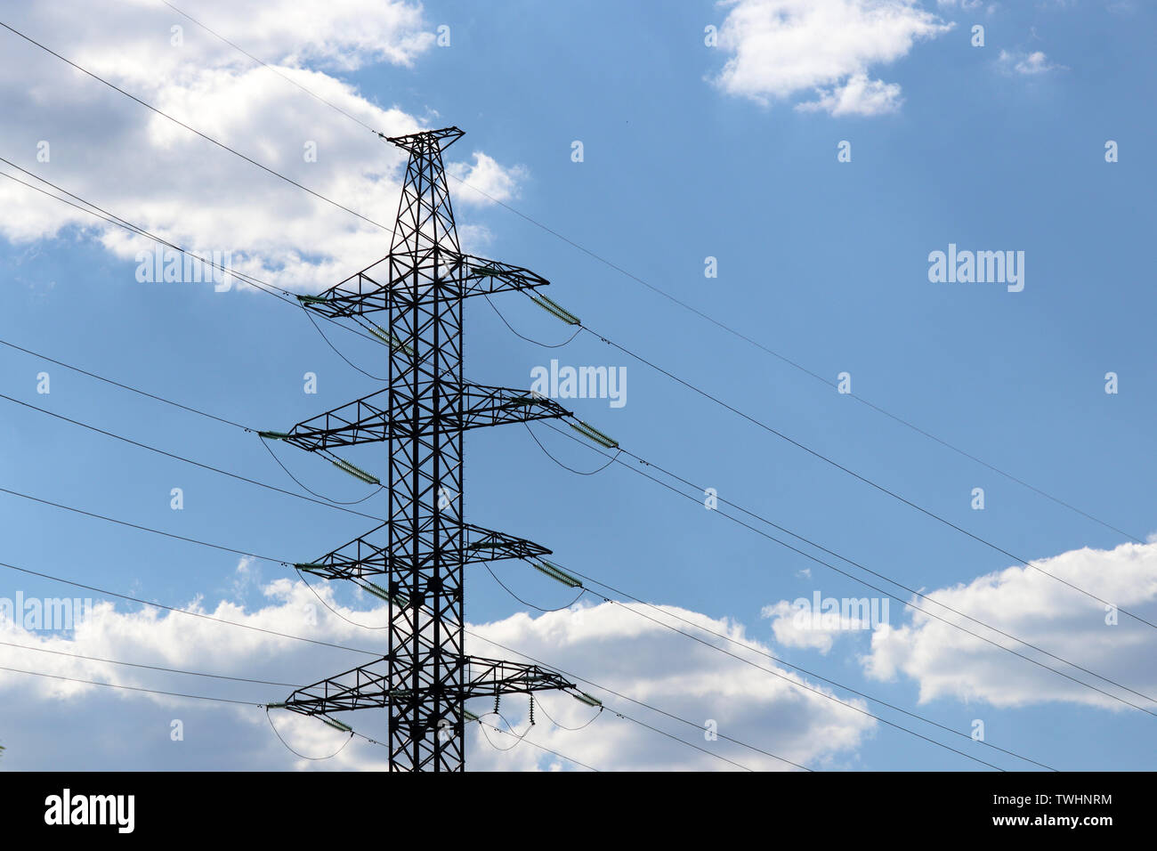 Alta tensione della linea di alimentazione supporti con fili elettrici sullo sfondo del cielo blu con nuvole bianche. Linee di trasmissione di energia elettrica, alimentazione Foto Stock