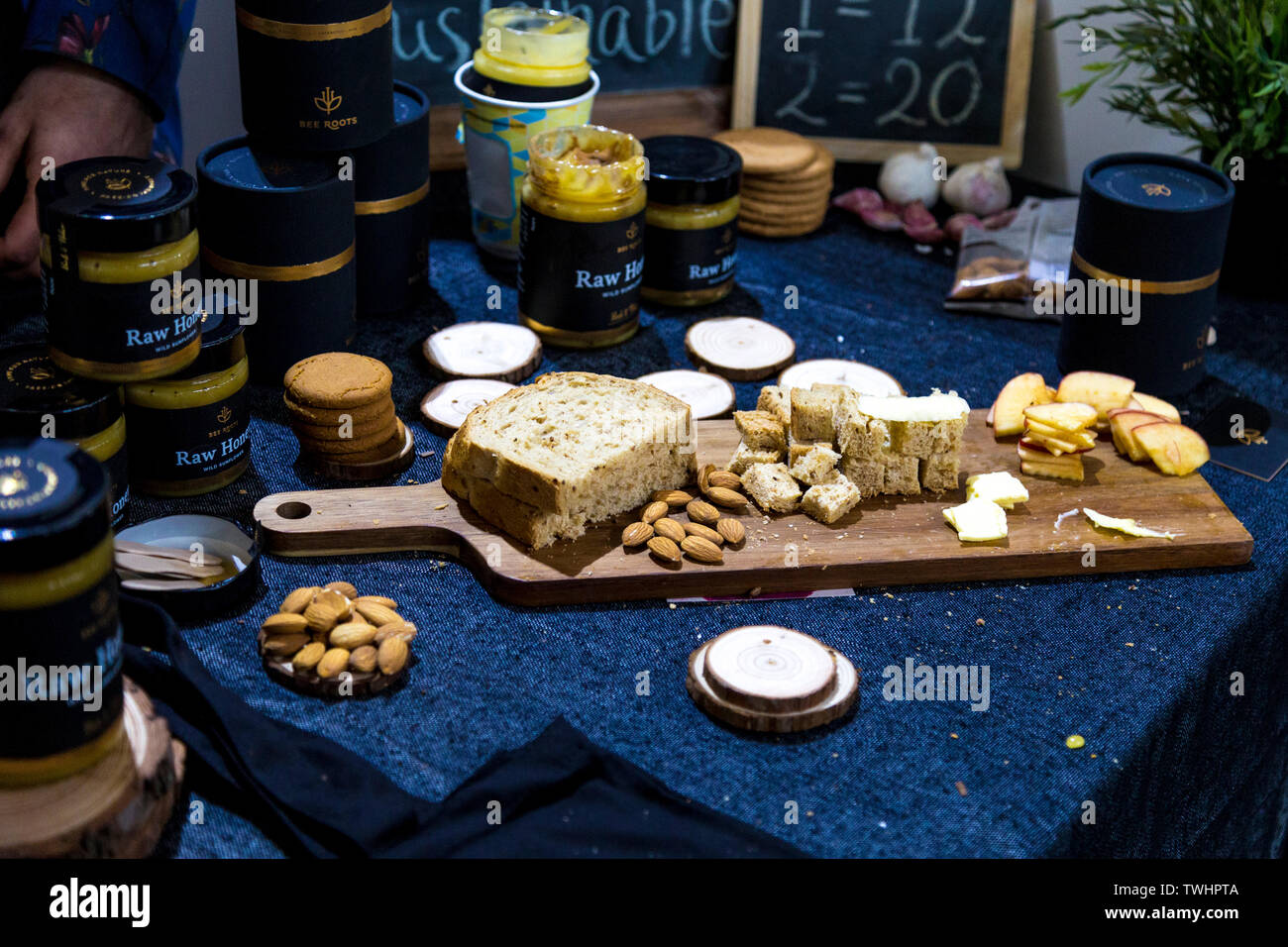 Materie miele stand (Bee radici), tagliere con pane, frutta a guscio e frutta, FesTeaVal 2019 al Dock di tabacco, London, Regno Unito Foto Stock