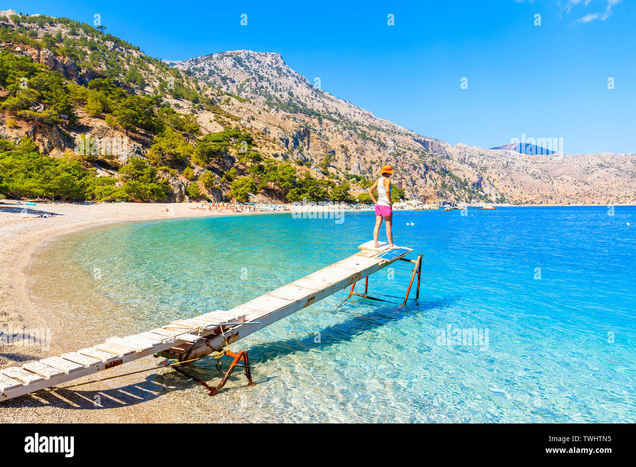 Giovane donna in piedi sul piccolo pontile in legno a Apella beach, Karpathos Island, Grecia Foto Stock