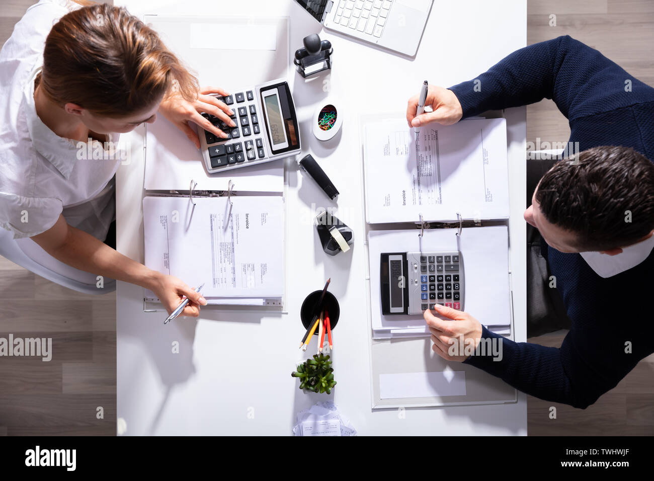 Alta Vista angolo di maschio e femmina imprenditori calcolo fattura con calcolatrice in ufficio Foto Stock