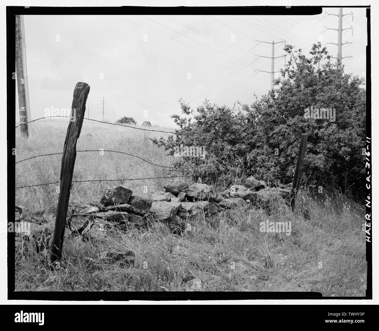 Vista laterale del rock recinto e associati tre filamenti del filo spinato; VISTA DA NORD-EST. - Strada Placerville, White Rock Road tra Clarksville e White Rock, El Dorado Hills, El Dorado County, CA Foto Stock