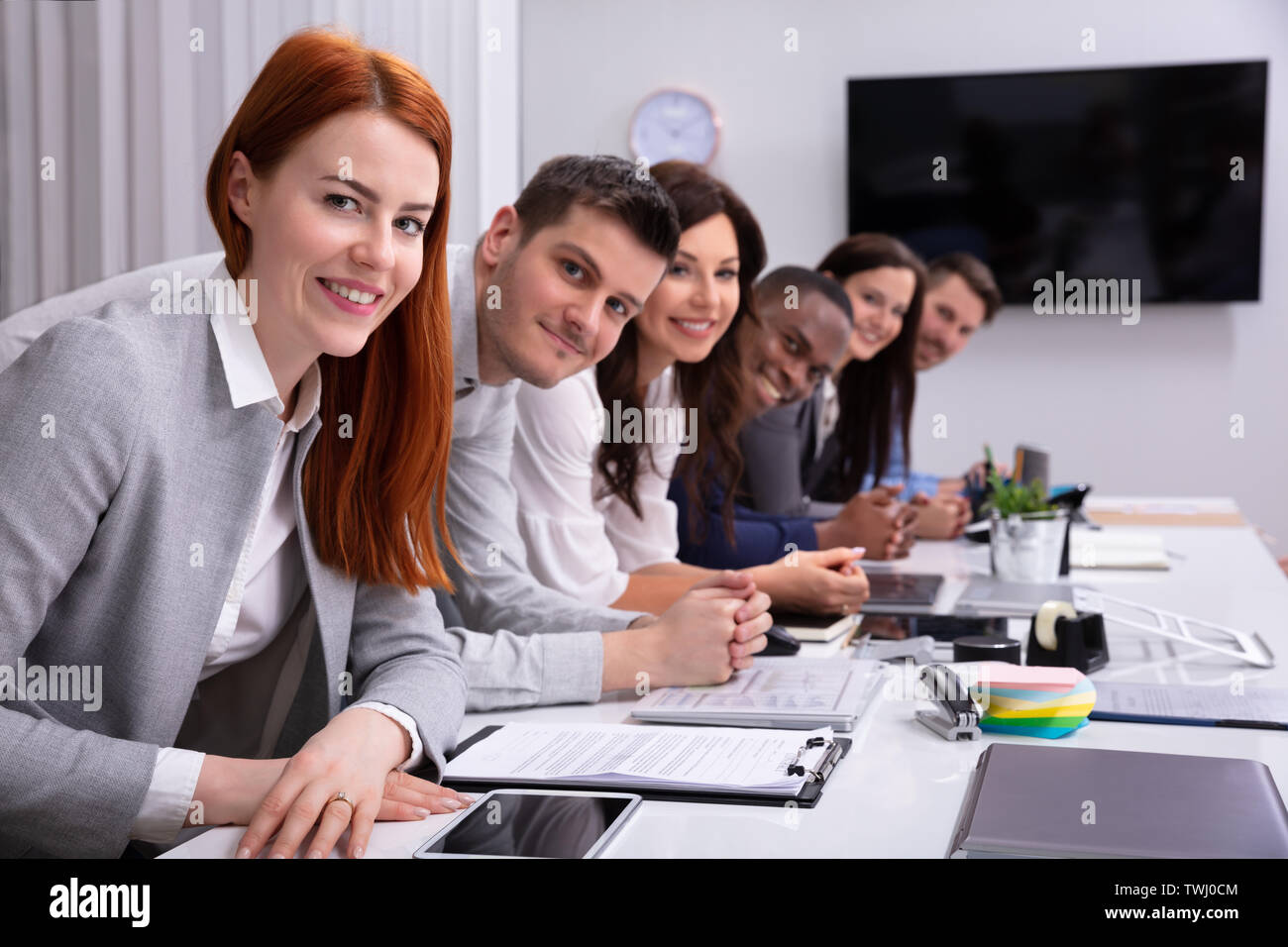 Gruppo multirazziale di happy businessman seduti insieme in fila guardando la fotocamera Foto Stock