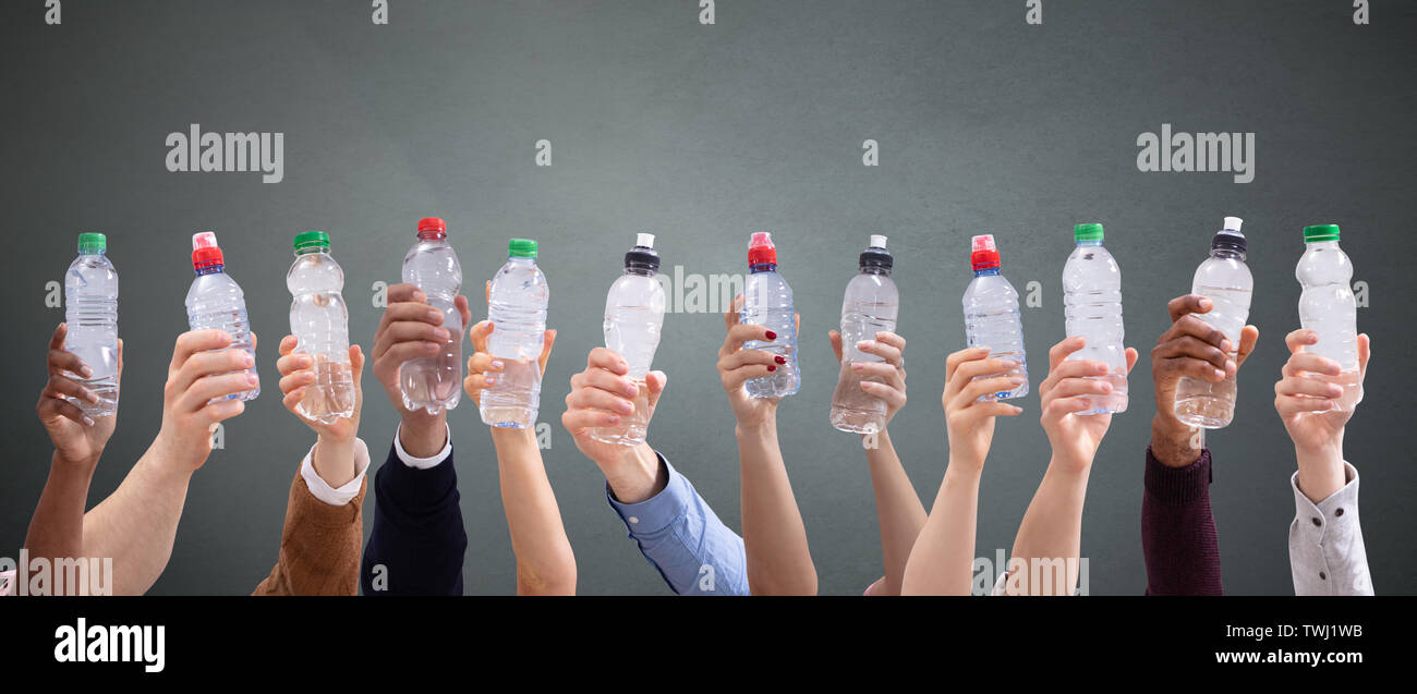 Gruppo di diverse persone che trattengono le bottiglie di acqua in una fila contro lo sfondo di colore verde Foto Stock