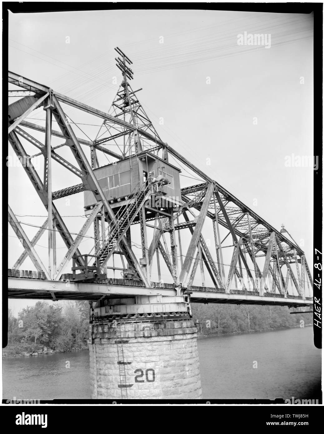 Mostra vista parziale laterale del ponte girevole in posizione aperta. L'operatore's house si trova nel centro di ponte di travatura reticolare, direttamente sopra il centro del perno di muratura di pietra Pier. Nota i due (2) centro supporti con i carichi di travatura reticolare che viene erogata al tamburo tramite un sistema di distribuzione di travi. Il ponte girevole ruotava su un tamburo cilindrico supportato da rulli in esecuzione su di una pista circolare sul centro-pivot Pier. - Bridgeport Swing Span bridge spanning sul fiume Tennessee, Bridgeport, Contea di Jackson, AL Foto Stock