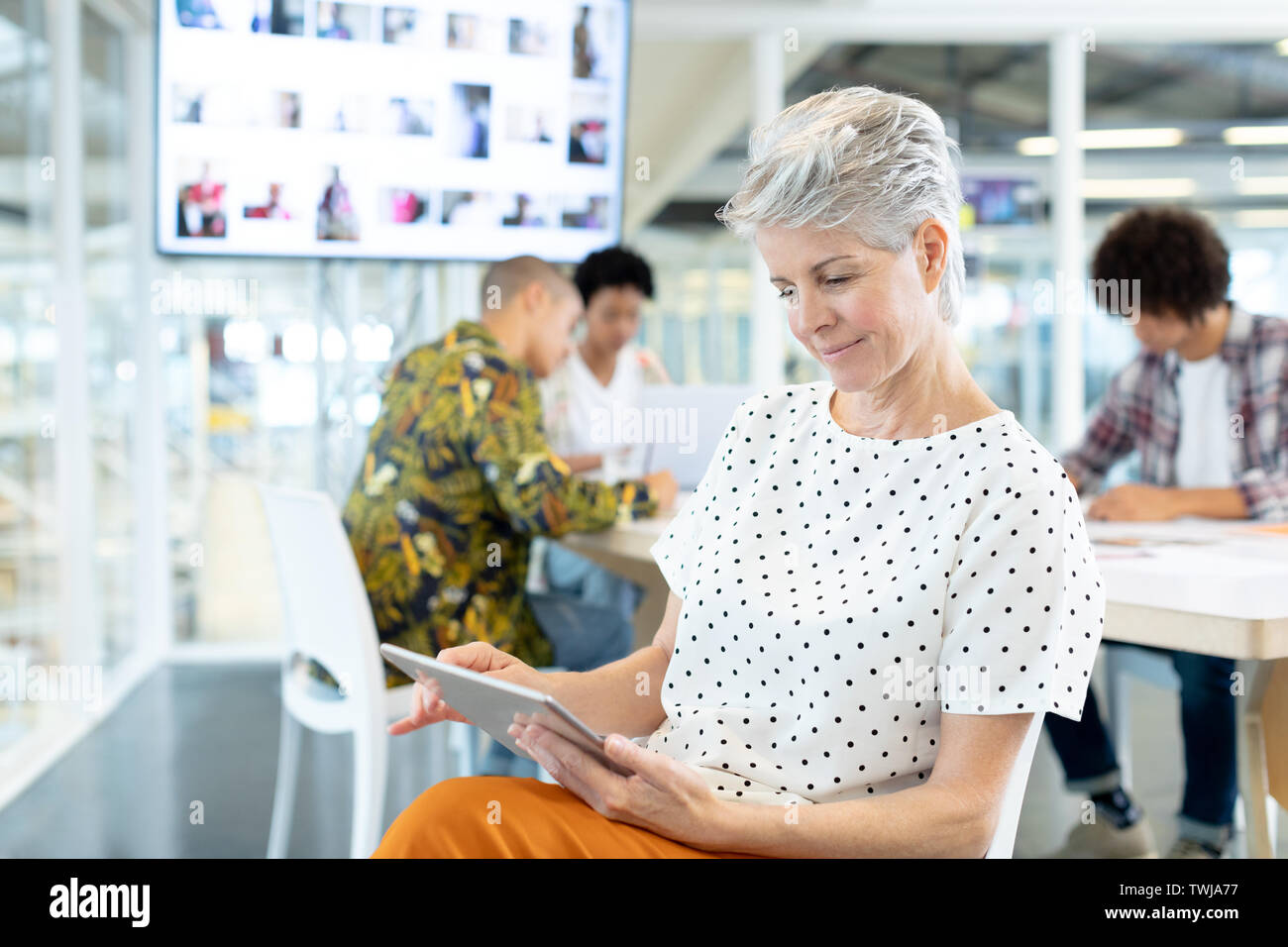 Femmina designer di moda con tavoletta digitale nella sala conferenze Foto Stock
