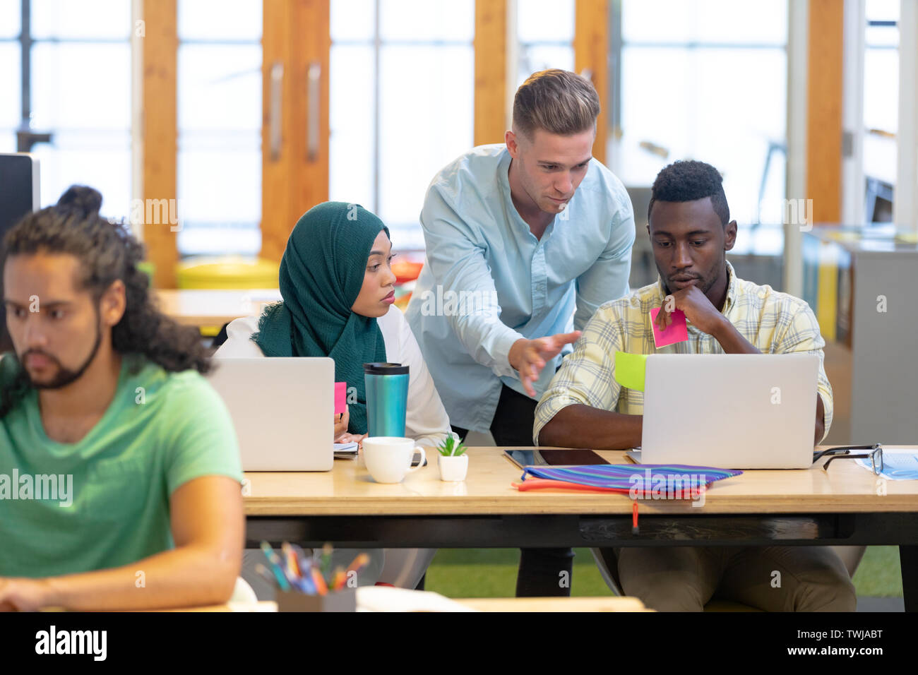 La gente di affari che lavorano insieme su laptop alla scrivania in un ufficio moderno Foto Stock