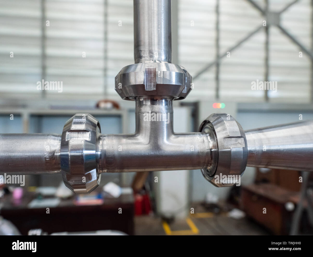 Connessione a T dei tubi in acciaio inox in un ambiente industriale. Profondità di campo. Foto Stock
