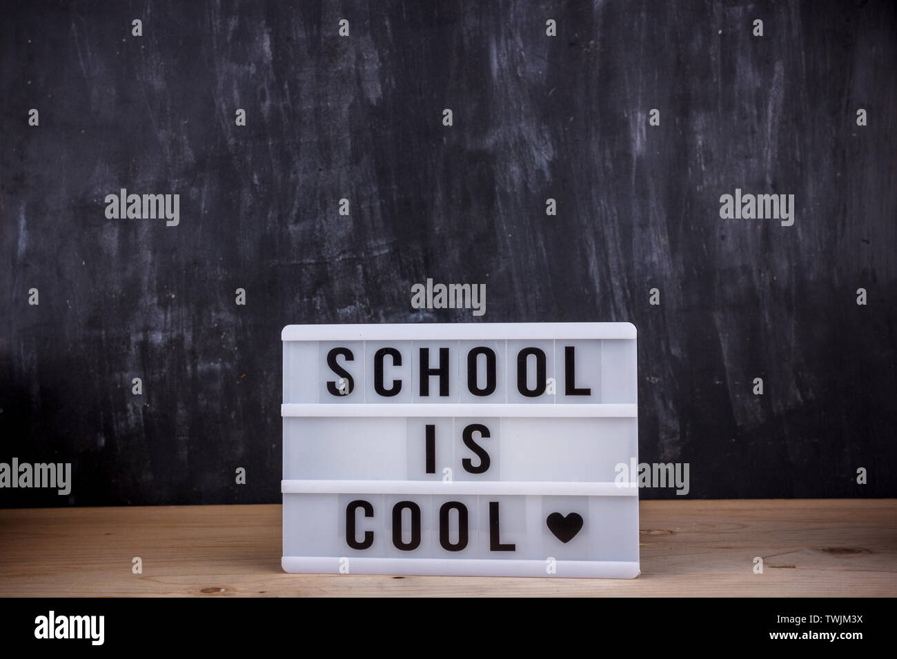 Lettering Scuola è cool. Nero scrivania sullo sfondo Foto Stock