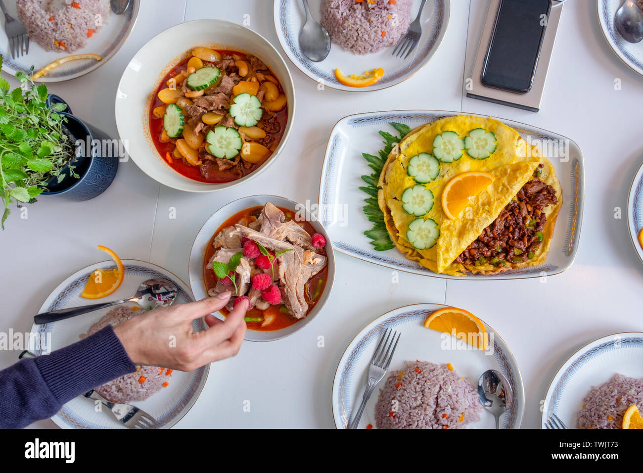 Mano a raggiungere la coppa con frittata di uova e la zuppa piccante di cibo in Asia Foto Stock