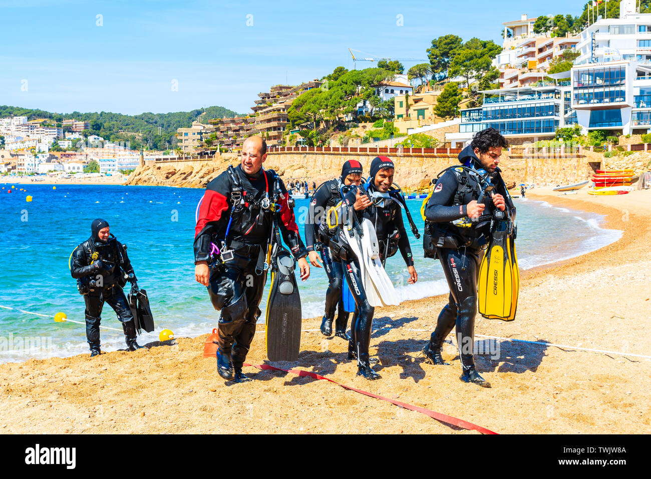 TOSSA DE MAR, Spagna - giu 3, 2019: Divers passeggiate fuori dall'acqua sulla spiaggia di Tossa de Mar città, Costa Brava, Spagna. Foto Stock