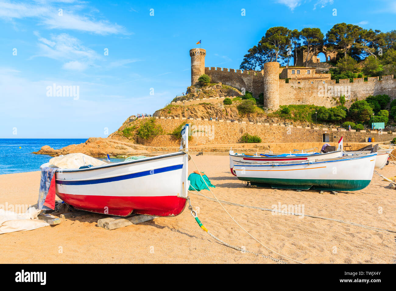 Barche di pescatori sulla spiaggia di sabbia dorata nella baia con castello in background, Tossa de Mar, Costa Brava, Spagna Foto Stock