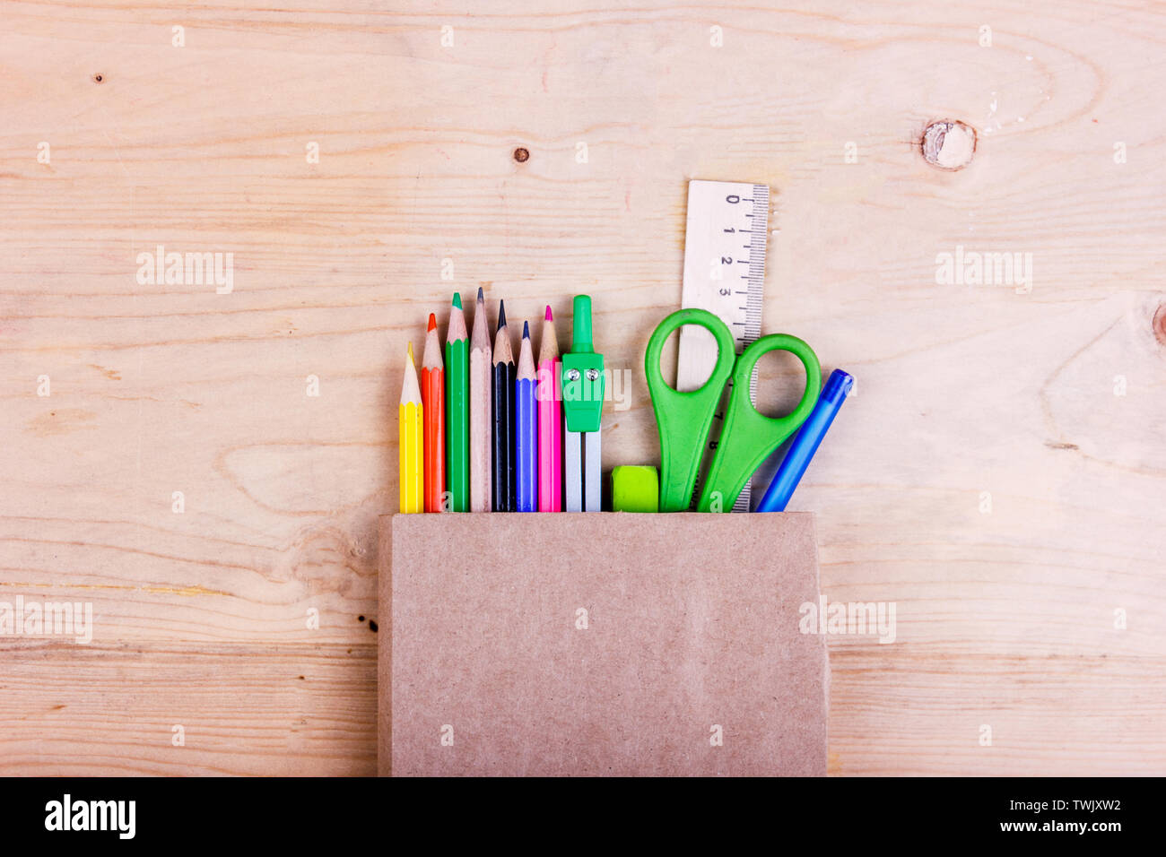 Il concetto di scuola. Matite colorate, forbici, righello compassi in un sacchetto di carta Foto Stock