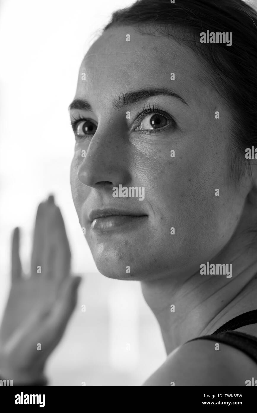 Primo piano in bianco e nero di una giovane e attraente donna bruna che fa una postura yoga con torsione spinale Foto Stock
