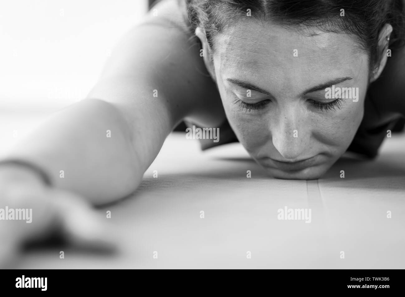 Primo piano di una giovane donna bruna che pratica yoga, faccia a faccia in giù sulla strada per una posa completa di Balasana o bambino Foto Stock