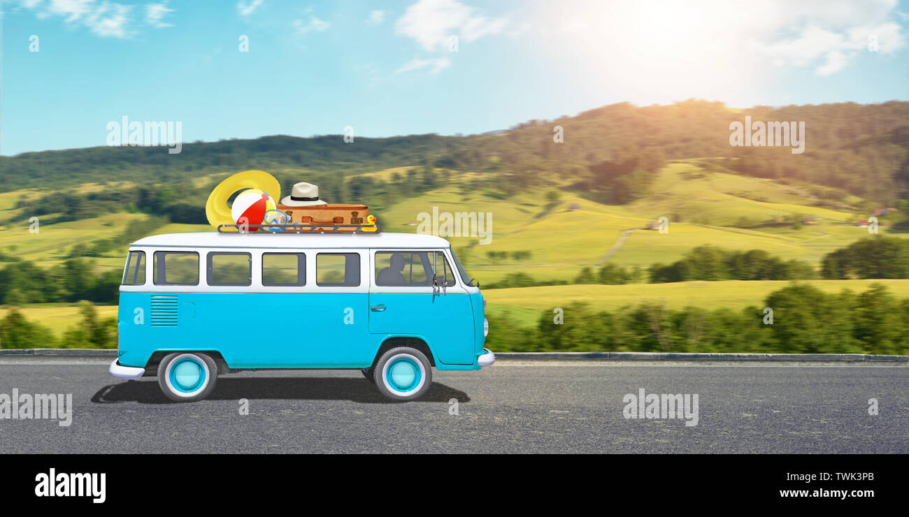 Viaggio con un van concetto. Il vecchio, blu, furgone hippie è sulla strada, bagagli è sul tetto. Paesaggio in background. Foto Stock