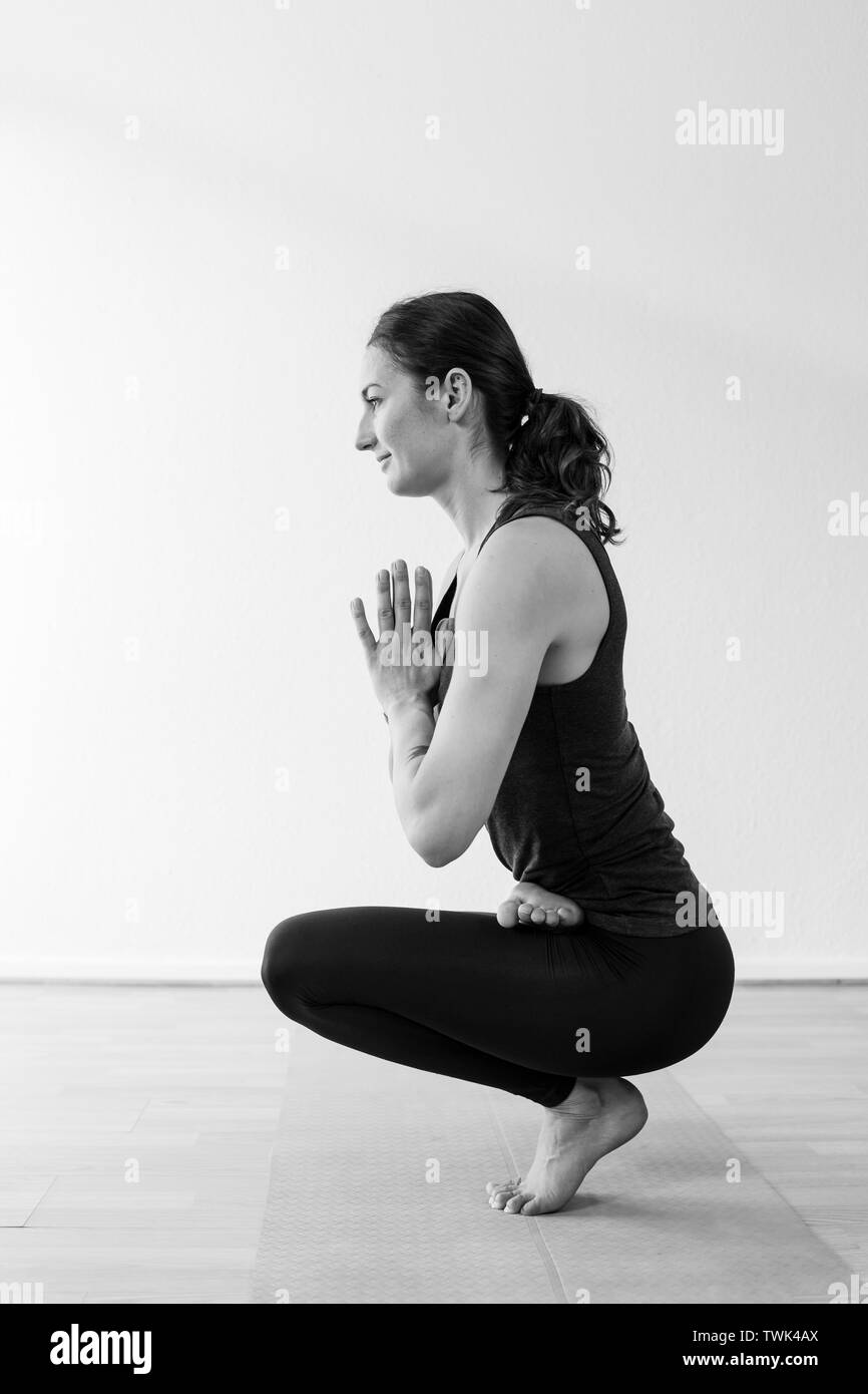 Vista laterale della punta punta asana o yoga asana con mani unite al centro del petto. Una bruna donna nella sua 30's a praticare yoga a casa. Foto Stock