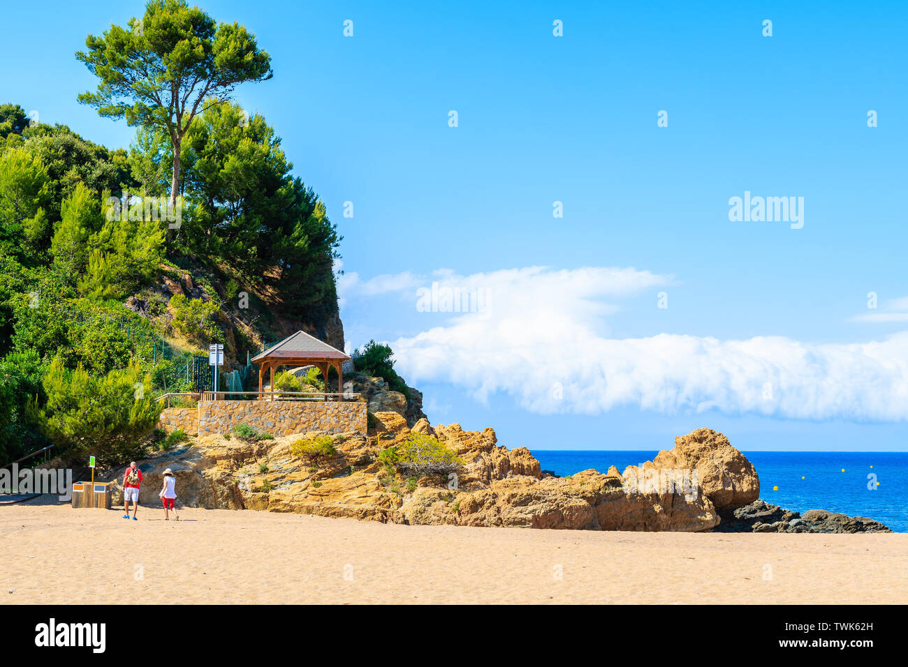 Coppia di turisti passeggiate sulla spiaggia di sabbia verso la scogliera percorso in Sa Riera village, Costa Brava, Spagna Foto Stock