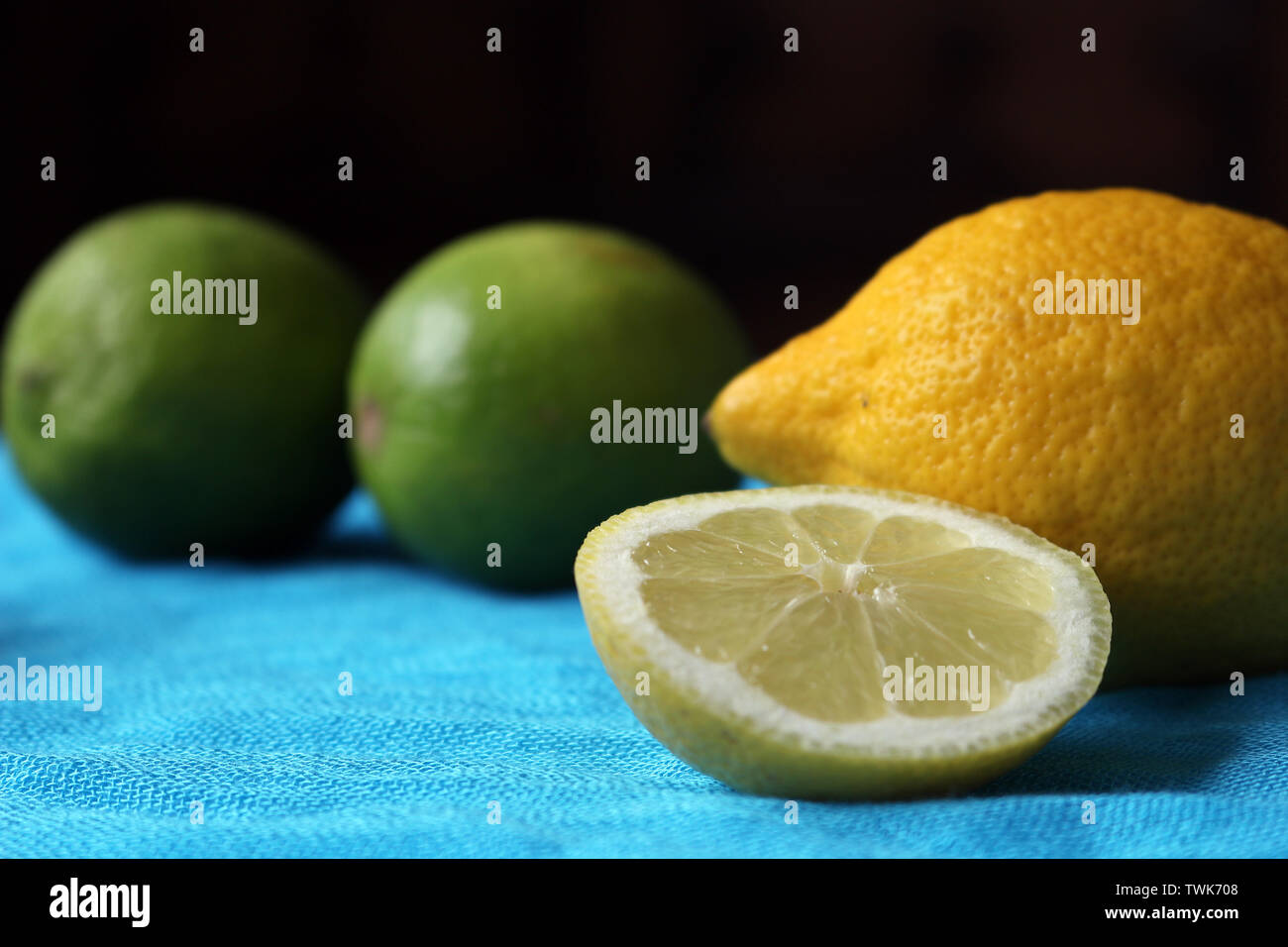 Un limone intero con un limone a fettine di fronte tutto il Limes su uno sfondo blu Foto Stock