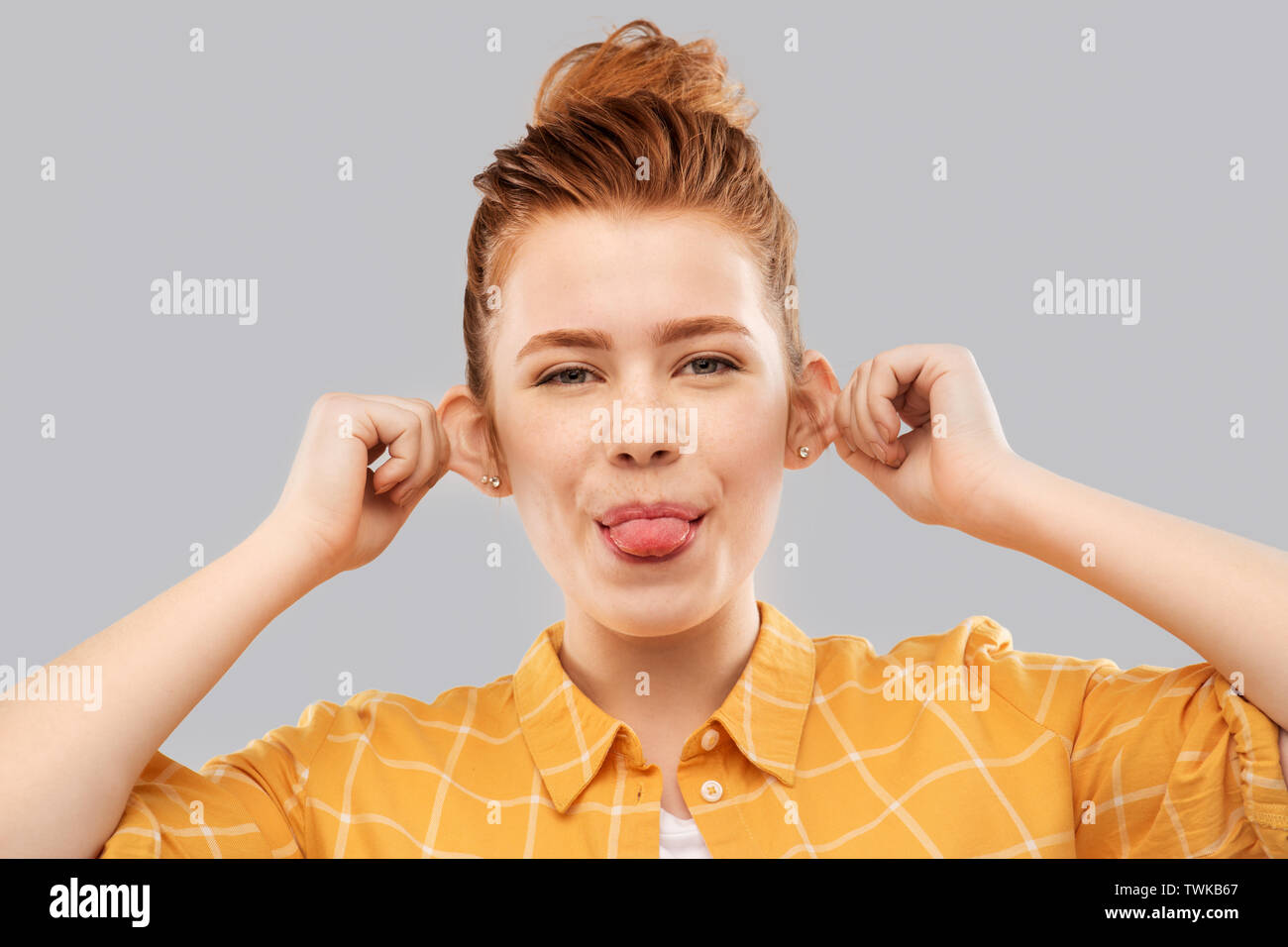 Sorridente dai capelli rossi ragazza adolescente che mostra la sua lingua Foto Stock