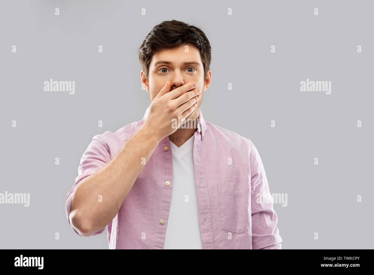Scioccato giovane uomo che copre la bocca con la mano Foto Stock