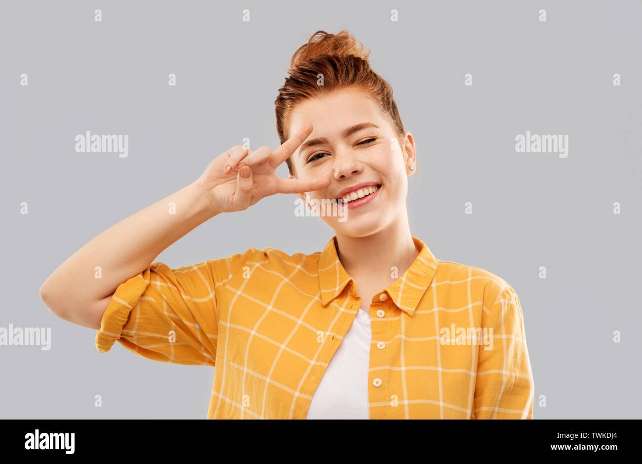 Sorridente dai capelli rossi ragazza adolescente che mostra la pace Foto Stock