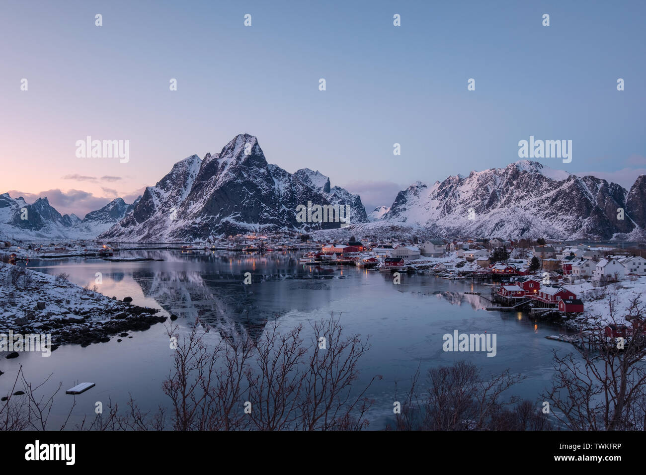 Villaggio di Pescatori con la montagna innevata sulla costa in inverno a Reine, Isole Lofoten in Norvegia Foto Stock