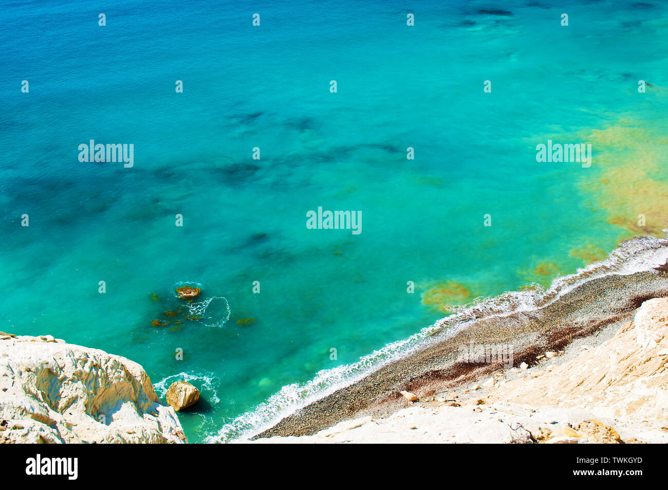 Vista da sopra sul brown spiaggia ghiaiosa e superficie del mare vicino a Paphos, Cipro. Sullo sfondo di un giallo e turchesi acque torbide. Autunno Caldo giorno. Girovagare Foto Stock