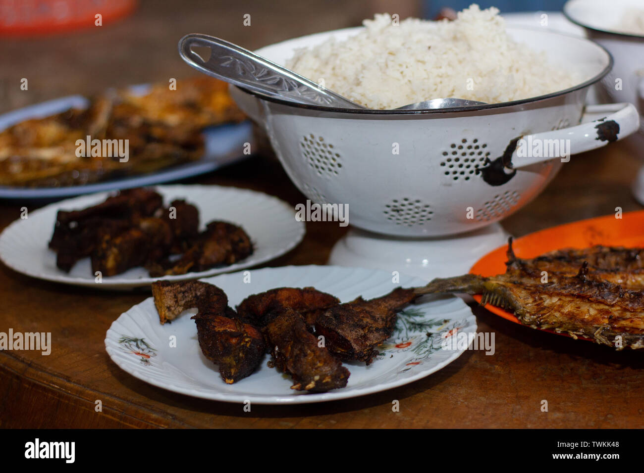 Cotte in casa il menu della cena da un villaggio di pescatori in Flores Indonesia. Il riso come alimento principale con piatti laterali in forma di pesce fritto Foto Stock