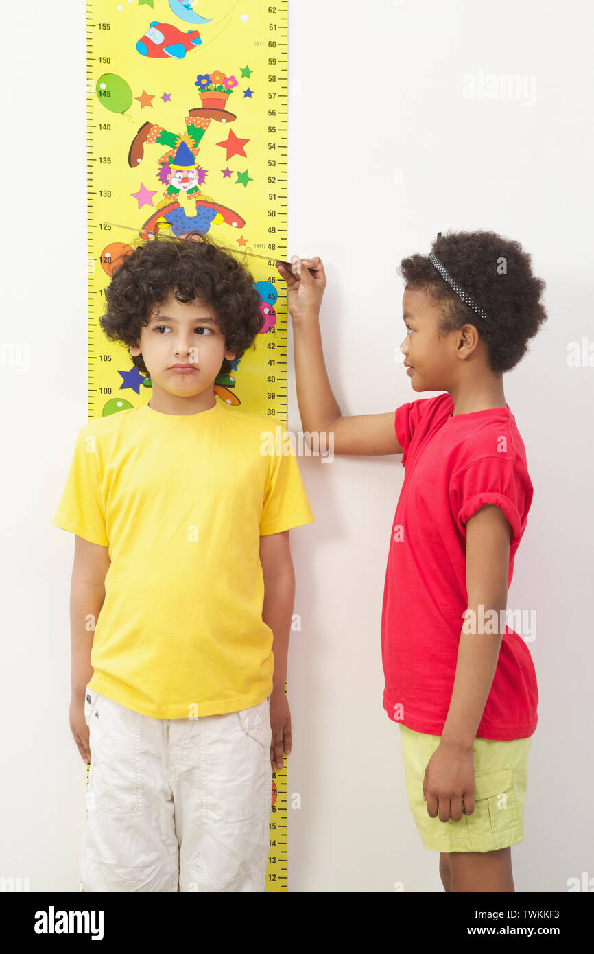 Ragazza che misura l'altezza del suo amico Foto Stock