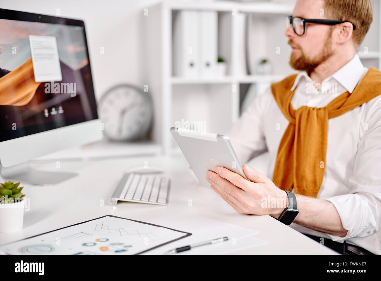 Età media imprenditore lavora con il tablet al computer in ufficio Foto Stock