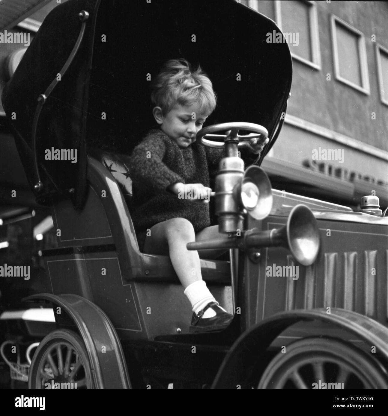 Little Boy su un auto d'epoca a gettone ride al di fuori di un negozio a Keswick, Lake District. c1965 Foto di Tony Henshaw Foto di Tony Henshaw Foto Stock