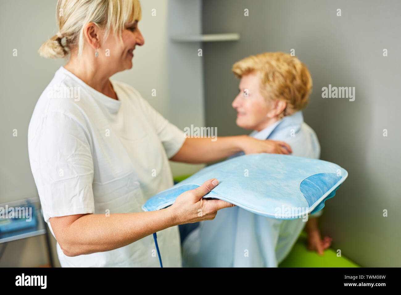 Non medico con senior della donna come un paziente in terapia magnetica nella medicina naturale Foto Stock