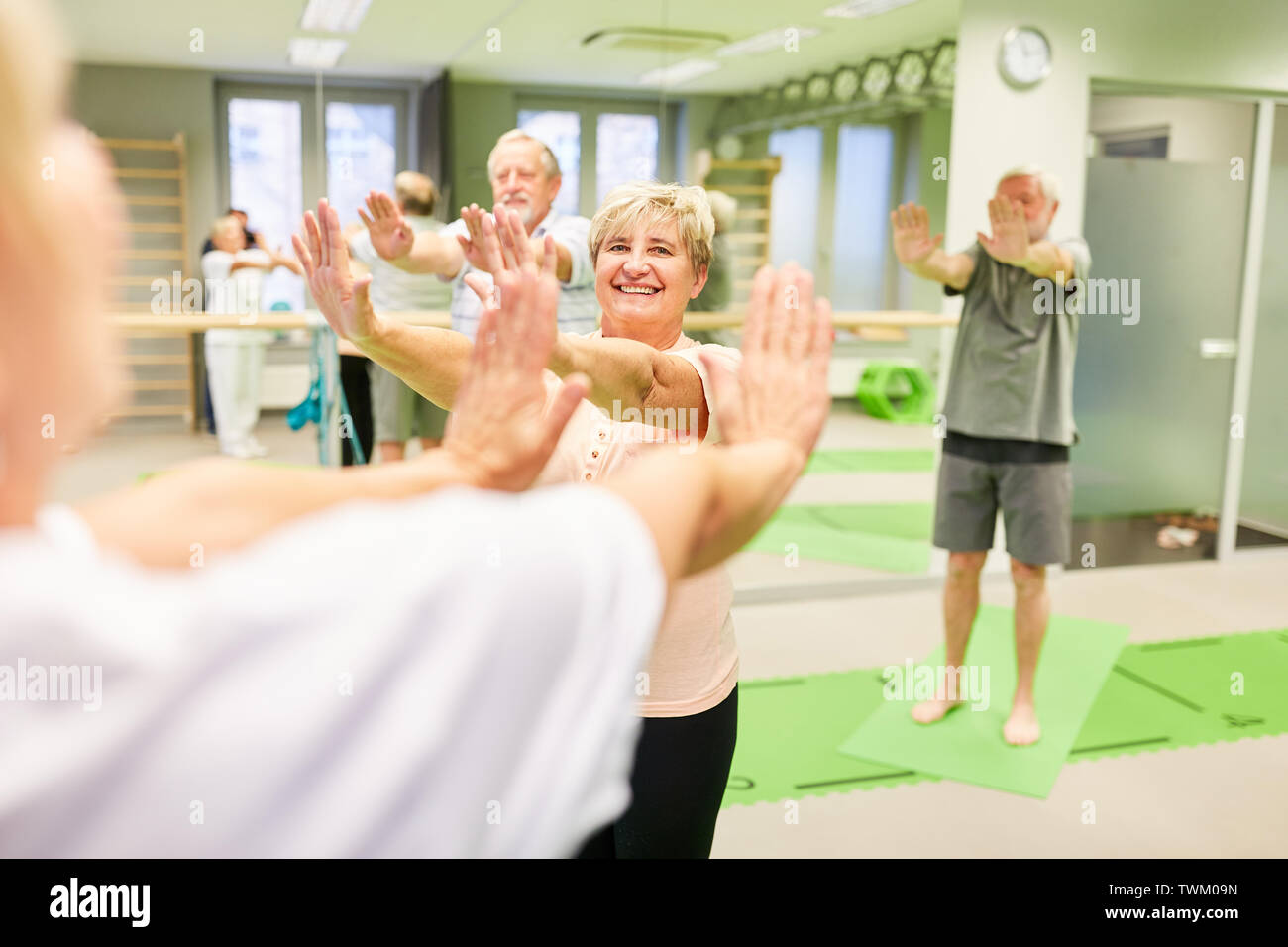 Gli anziani fare un esercizio di indietro in fisioterapia sotto la guida del formatore Foto Stock