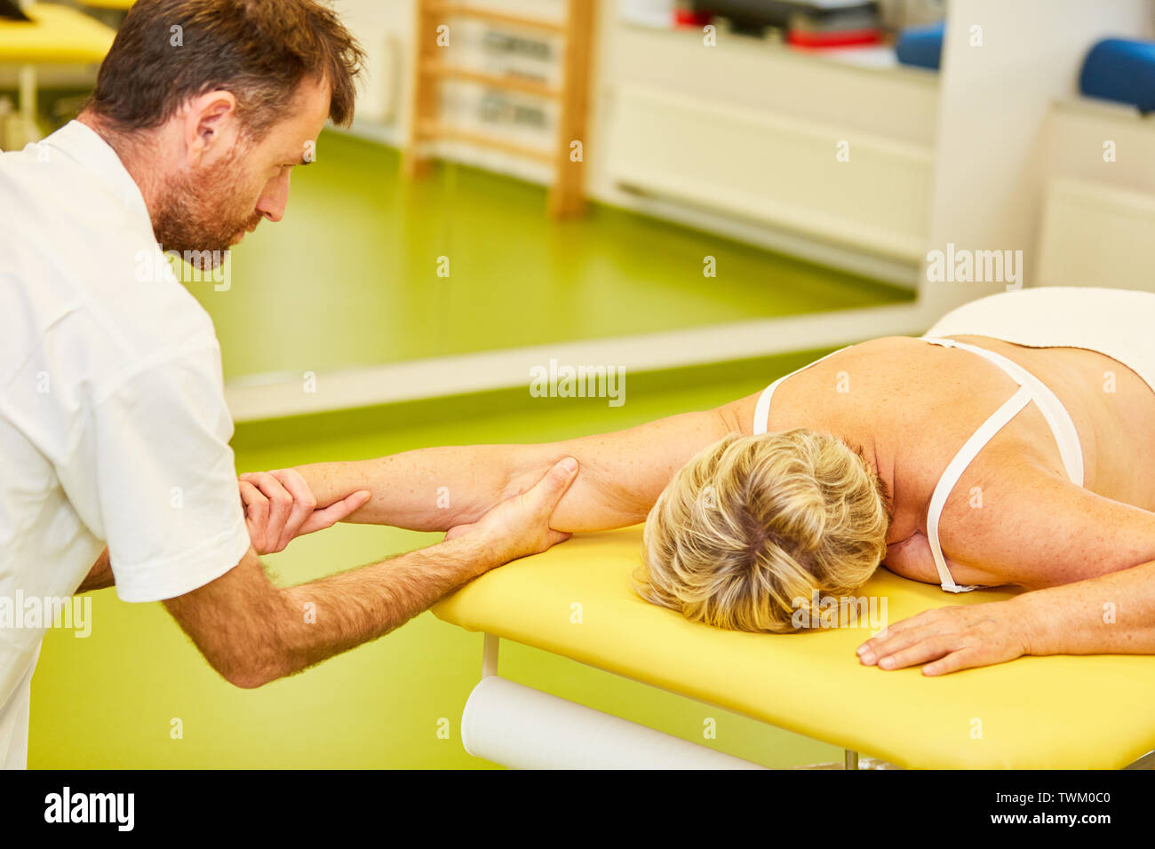 Fisioterapista con competenza tratta il paziente sul gomito con una impugnatura chiropratica Foto Stock